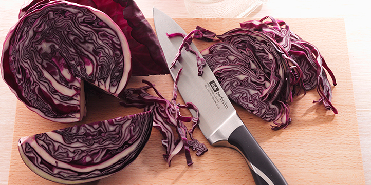 Rotkohl schneiden Rotkohl mithilfe eines großen Kochmessers in feine Streifen schneiden